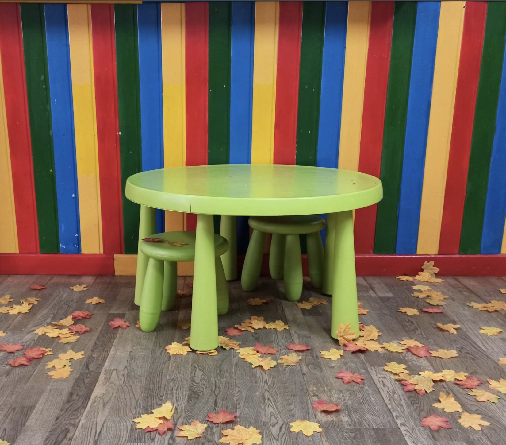 Mesa infantil verde con hojas de otoño sobre el suelo