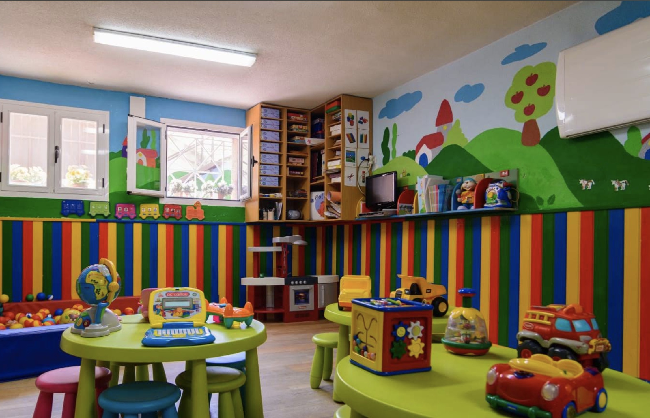 Aula amplia con juguetes, mesas y decoración infantil